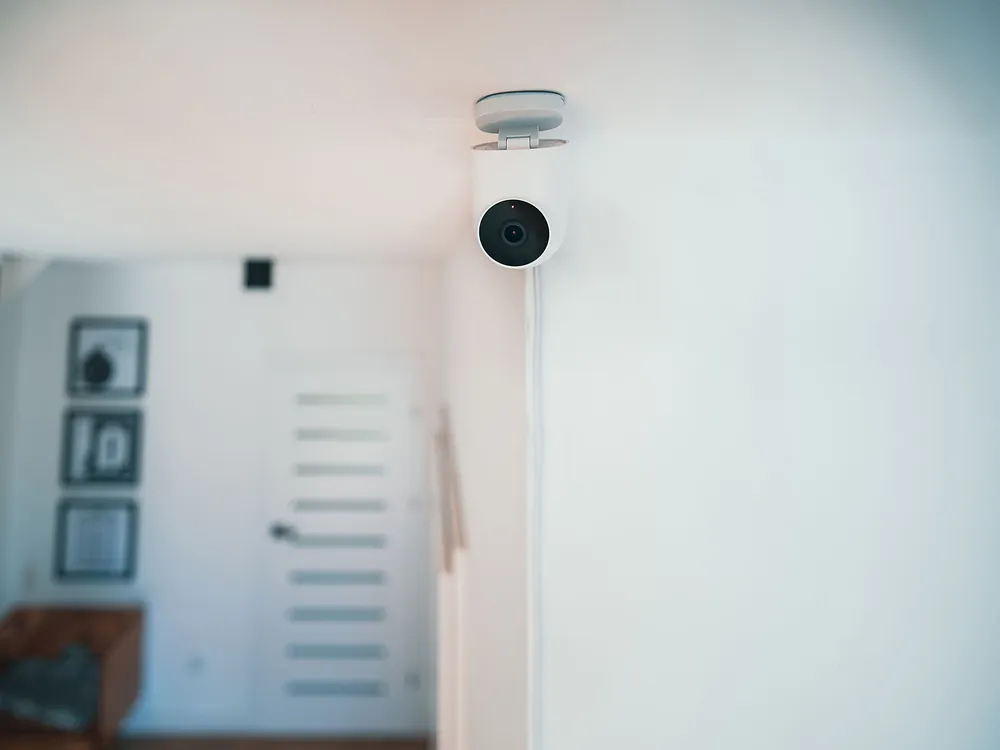 A small indoor security camera on a ceiling corner