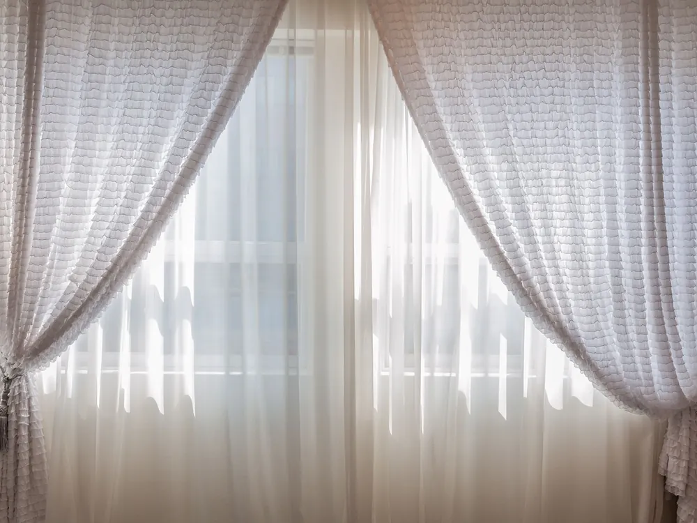 Sheer curtains drawn back from a sunlit window
