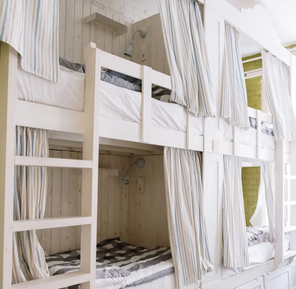 A shared dorm room with bunk beds and privacy curtains