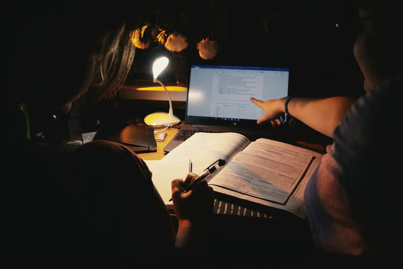 A student studying late at night by a desk lamp